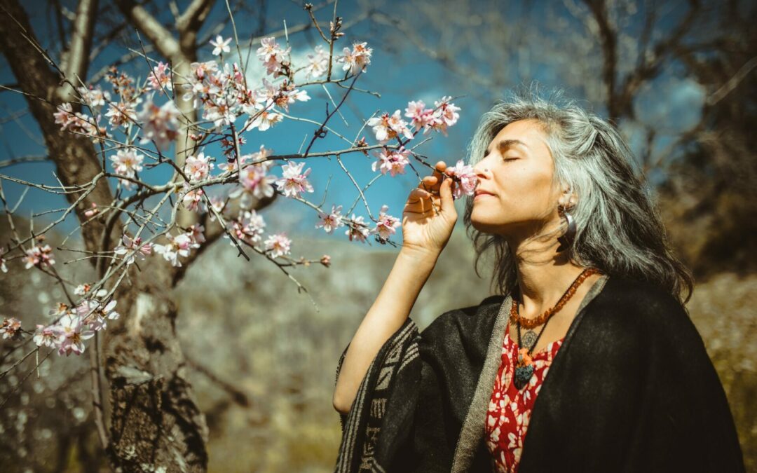 middle-aged woman smelling tree blossoms on a relaxing walk