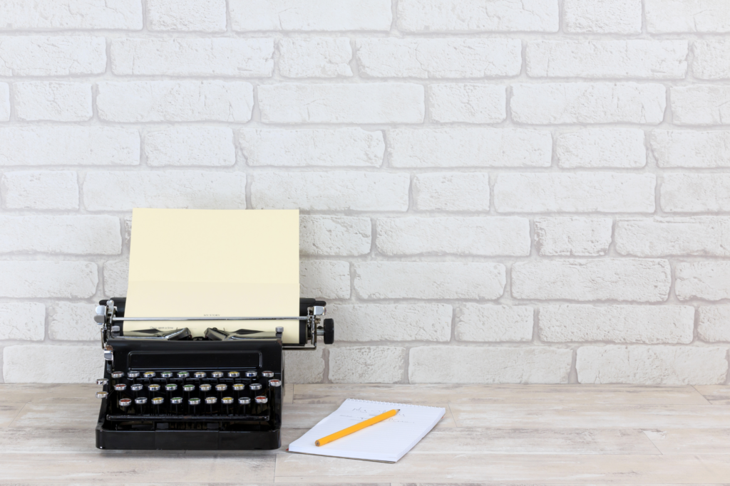 manual typewriter against a white brick background