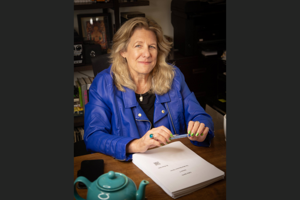 Diane Hatz holding pen with typed manuscript